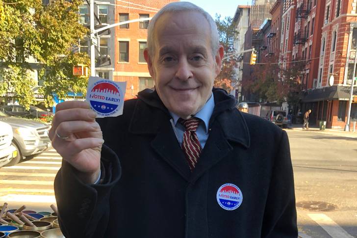 A man holding up a sticker indicating that he voted.